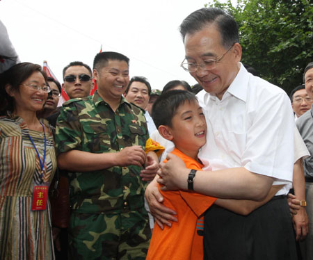 Chinese Premier Wen Jiabao (R Front) embraces Wang Shichen, a 12-year-old primary school pupil of grade six, when he inspects the resettlement at Meirui Textile Company in Mianyang, a city in quake-hit southwest China's Sichuan Province, June 6, 2008. (Xinhua Photo)