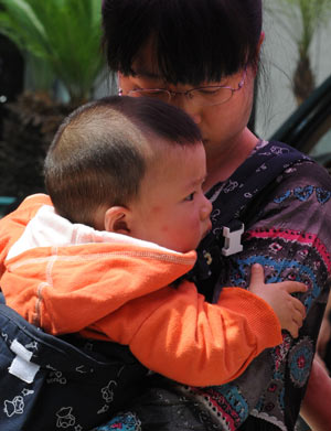 A woman mourns while cuddling her baby during a silent tribute in Guiyang, capital of southwest China's Guizhou Province, May 19, 2008. 